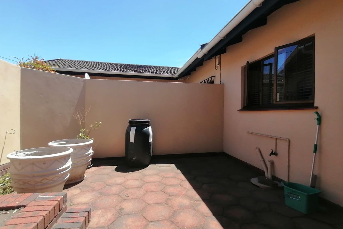 A private rear courtyard featuring paved flooring, boundary walls, and external plumbing connections, offering a functional outdoor space for the townhouse.