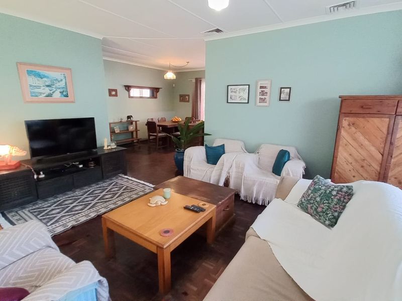 Spacious open-plan living and dining area featuring classic parquet flooring and neutral wall tones, offering a versatile layout for family living.