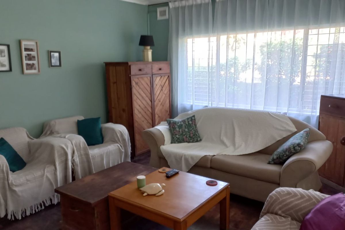 A comfortable living room featuring a large window with security bars and classic cornice detailing, offering a bright and functional space.