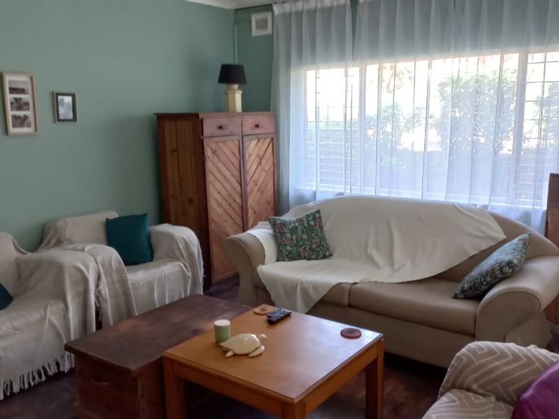 A comfortable living room featuring a large window with security bars and classic cornice detailing, offering a bright and functional space.