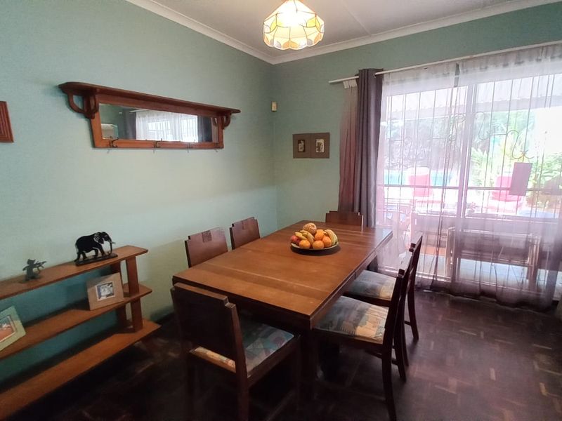 A dining room featuring classic parquet flooring, a built-in wall mirror, and a sliding glass door providing access to the outdoor area.