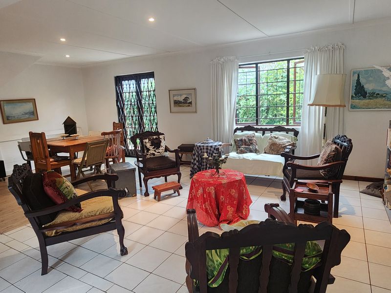 Spacious open-plan living and dining area featuring neutral tiled flooring, recessed lighting, and large windows with security bars.