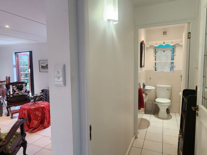 A view from the hallway looking into an open-plan living area and a small guest bathroom with tiled flooring and classic architectural details.
