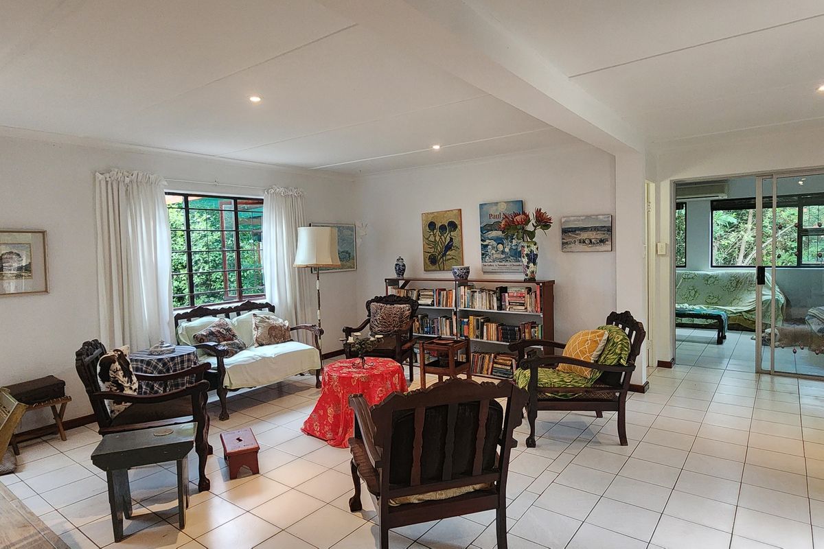 Spacious living area featuring neutral tiled flooring, recessed lighting, and large windows that provide natural light and garden views.
