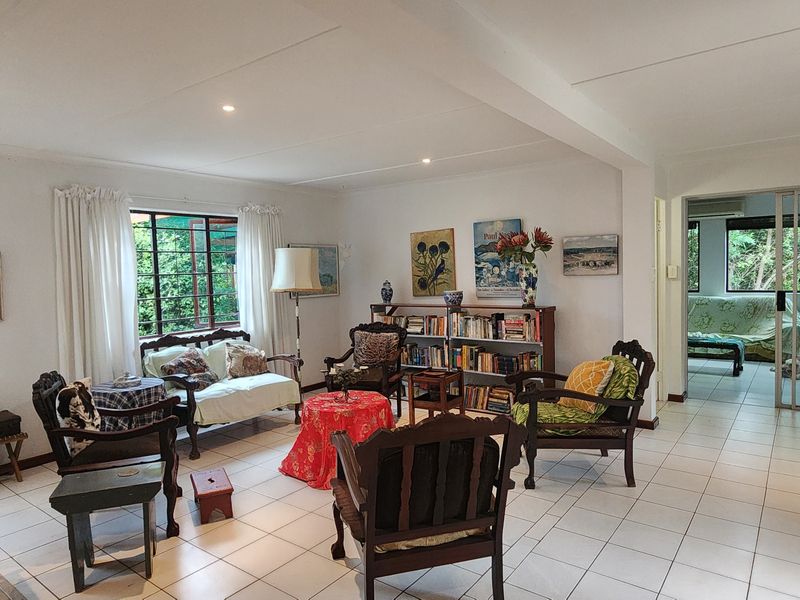 Spacious living area featuring neutral tiled flooring, recessed lighting, and large windows that provide natural light and garden views.