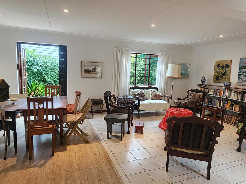 Spacious open-plan living and dining area featuring a mix of tiled and laminate flooring, recessed lighting, and direct access to the garden via french doors.