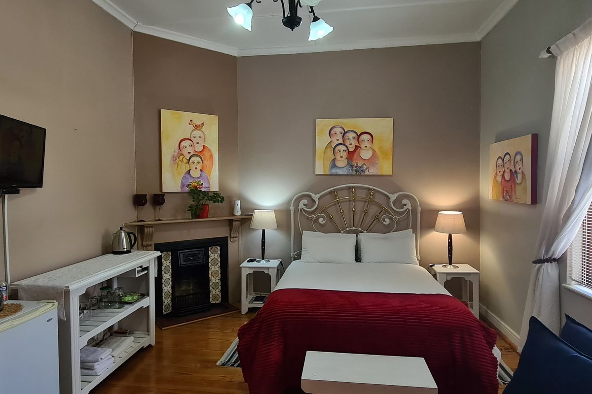 A well-maintained bedroom featuring hardwood flooring, a built-in fireplace with a mantel, and large windows allowing for natural light.