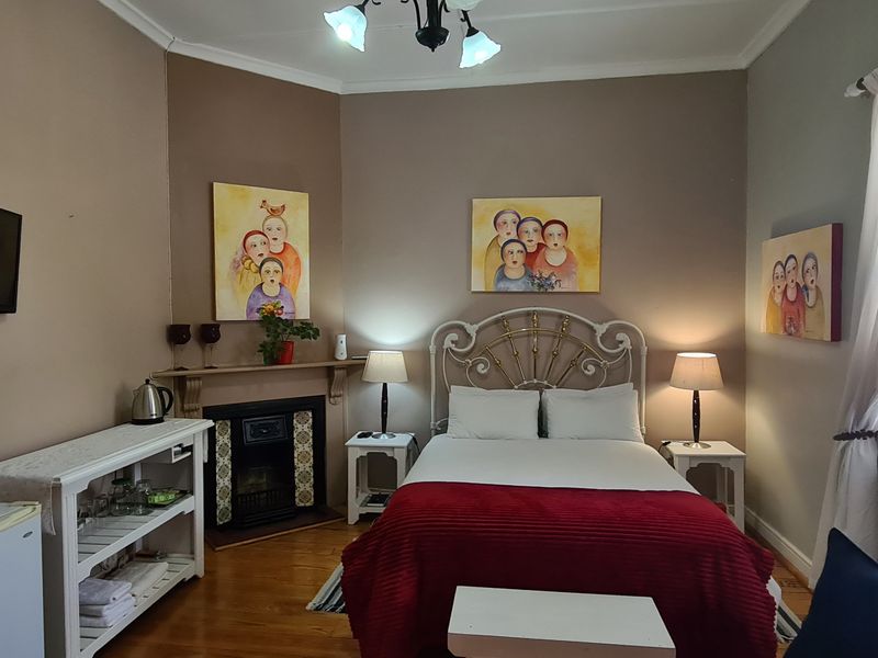 A well-maintained bedroom featuring hardwood flooring, a built-in fireplace with a mantel, and large windows allowing for natural light.