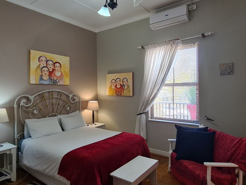 A cozy bedroom featuring a fireplace, split-system air conditioning unit, and timber flooring.