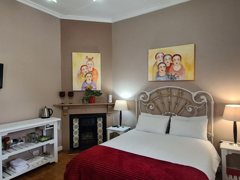 A cozy bedroom featuring a built-in fireplace with a mantelpiece, hardwood flooring, and neutral wall tones.