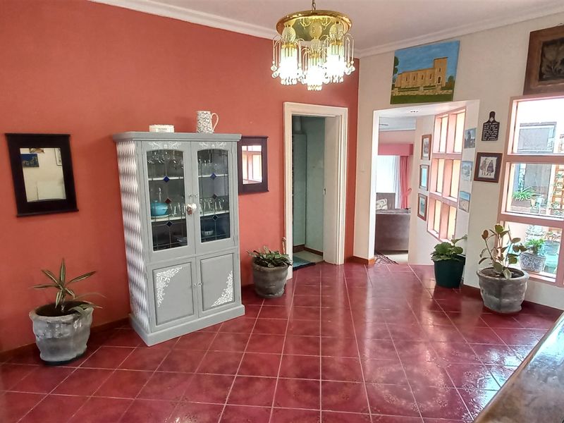 Entrance hall featuring terracotta-style tiled flooring, decorative chandelier, and large multi-pane windows providing natural light and views into the courtyard.