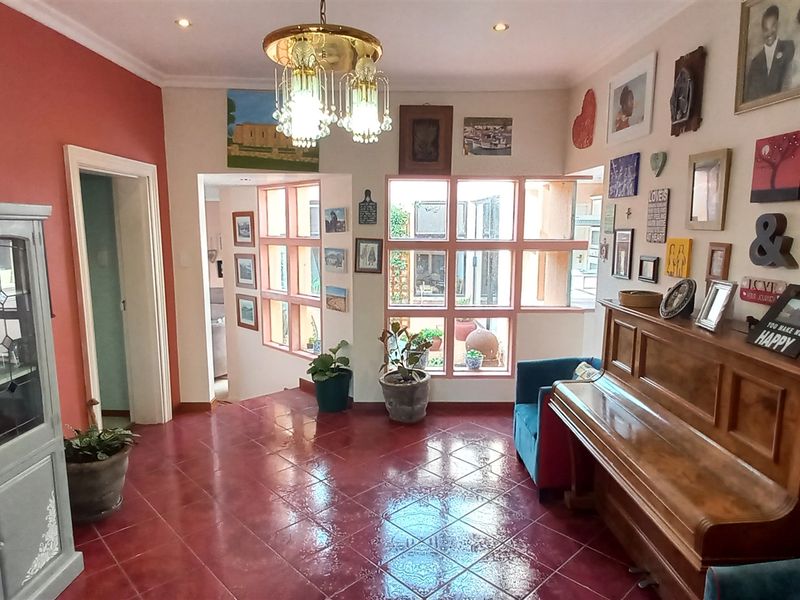 A spacious entrance hall featuring terracotta-style tiled flooring, recessed ceiling lighting, and a large multi-pane window looking out toward an internal courtyard area.