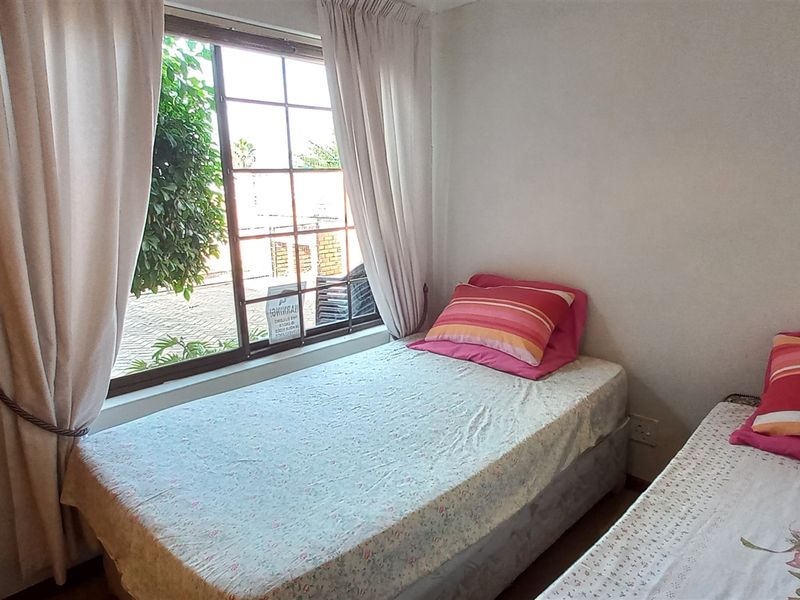 A bedroom featuring a window with security bars and built-in cabinetry.
