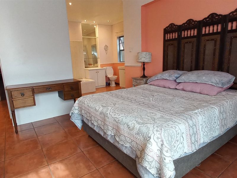Spacious bedroom featuring terracotta floor tiles, integrated en-suite bathroom access, and neutral wall finishes.