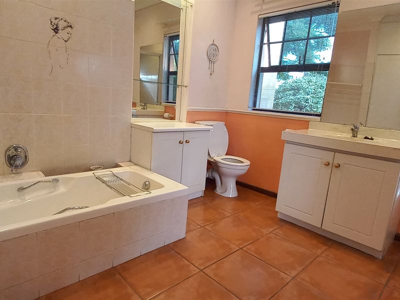 A functional bathroom featuring a built-in bathtub, dual vanity cabinets, a toilet, and large wall-mounted mirrors.