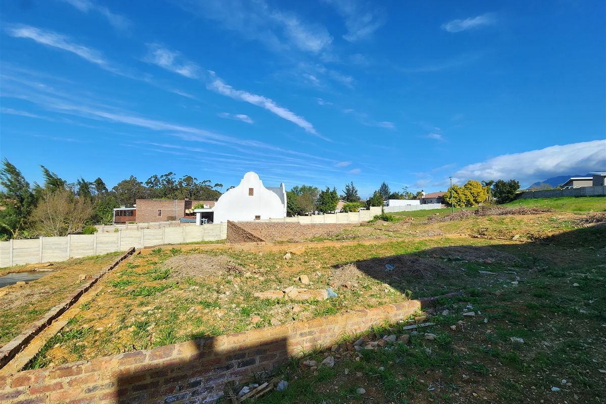 A vacant residential plot featuring brick retaining walls and precast concrete boundary fencing, ready for development.