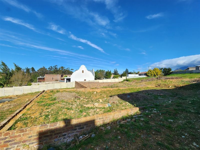 A vacant residential plot featuring brick retaining walls and precast concrete boundary fencing, ready for development.