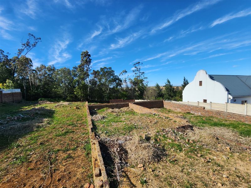 Vacant residential land featuring partial brick foundation walls and boundary fencing, offering a clear site for future development.