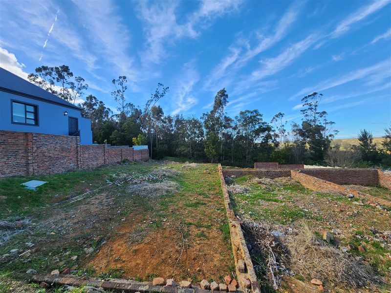 A vacant residential plot featuring established brick boundary walls and a gentle slope, ready for development.