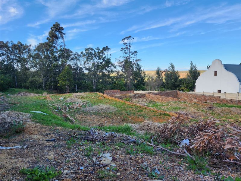 A vacant residential plot featuring partial brick foundation walls, ready for development in a quiet, established neighborhood setting.