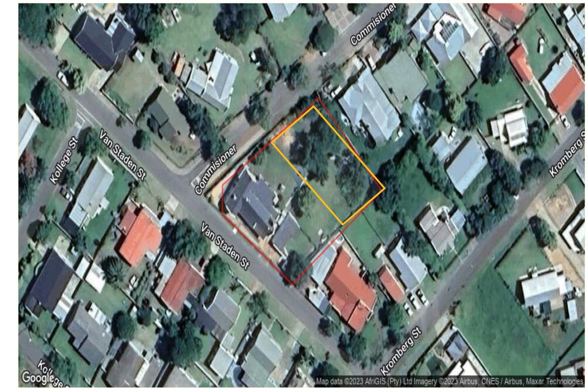 Aerial view of a residential vacant land plot situated on a corner stand, featuring established trees and defined boundary lines.