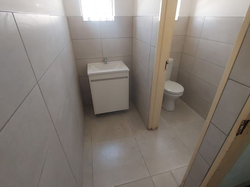 A functional bathroom featuring tiled walls and flooring, a white vanity cabinet with a basin, and a standard toilet.