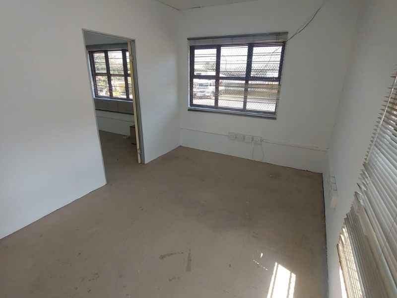 An empty office space featuring plain walls, aluminium window frames with blinds, and multiple electrical power points, suitable for a professional workspace.