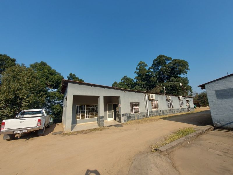 Front exterior view of a single-story commercial building featuring stone cladding, security bars, and multiple wall-mounted air conditioning units.