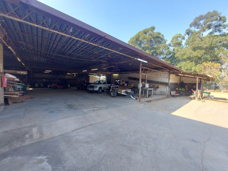 Large open-plan industrial utility space featuring a high corrugated metal roof, steel support structure, and expansive concrete flooring suitable for storage or workshop use.