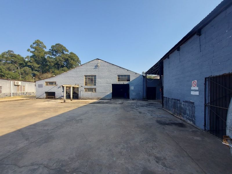 Exterior view of an industrial warehouse facility featuring a large concrete yard and blue painted masonry walls.