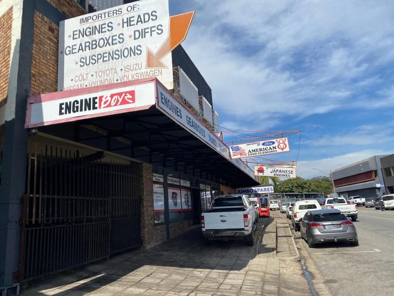 Front exterior view of a commercial automotive parts facility featuring prominent signage, a covered walkway, and brick facade construction.