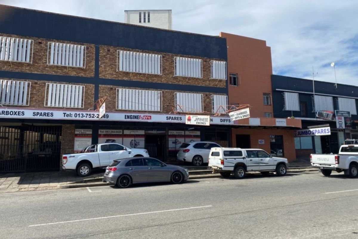 Commercial street-level storefront featuring brick facade, security shutters, and prominent signage, suitable for automotive parts or retail business operations.