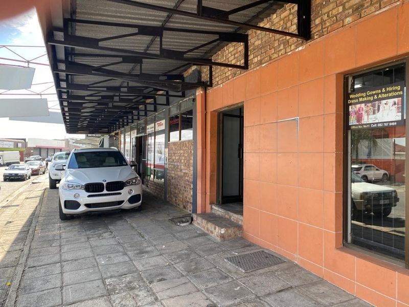 Commercial storefront exterior featuring exposed brick and tiled facade with a covered walkway and large glass display windows.