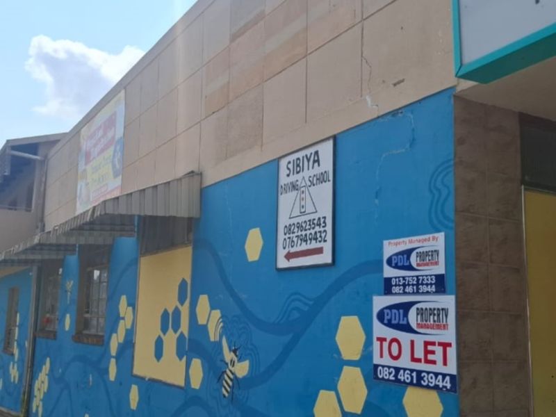 Exterior view of a commercial building facade featuring painted walls, signage, and an awning, currently available for lease.