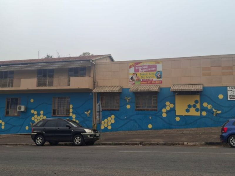 Street-facing commercial building facade featuring blue painted lower walls with honeycomb patterns, upper balcony, and security window grilles.