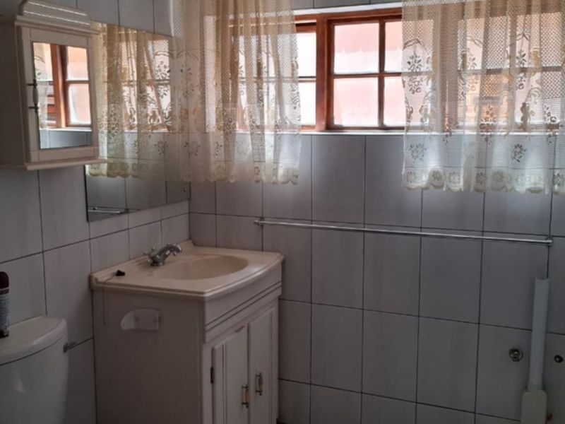 A functional bathroom featuring a vanity cabinet, basin, toilet, and tiled finishes, offering potential for modernization and cosmetic updates.