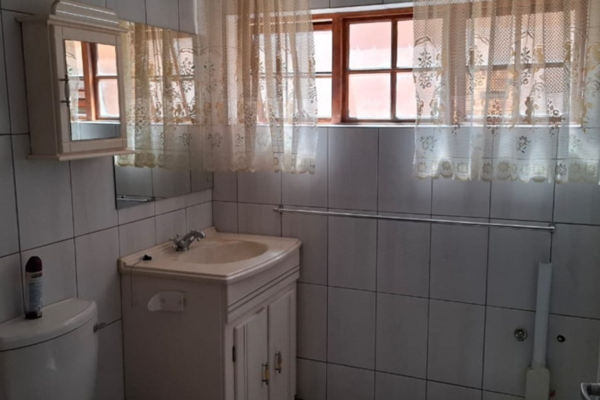 A functional bathroom featuring a vanity cabinet, basin, toilet, and tiled finishes, offering potential for modernization and cosmetic updates.