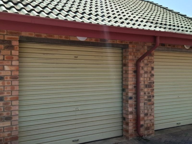 A double garage featuring face brick walls, a tiled roof, and two roller doors in a functional condition.