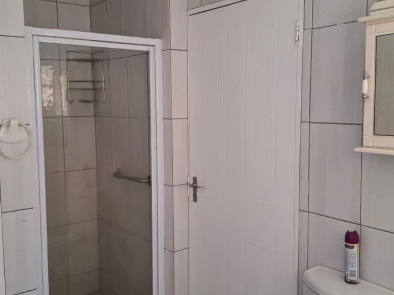 A functional bathroom featuring a shower enclosure, tiled walls, and a wall-mounted medicine cabinet, presenting a clean and practical layout.