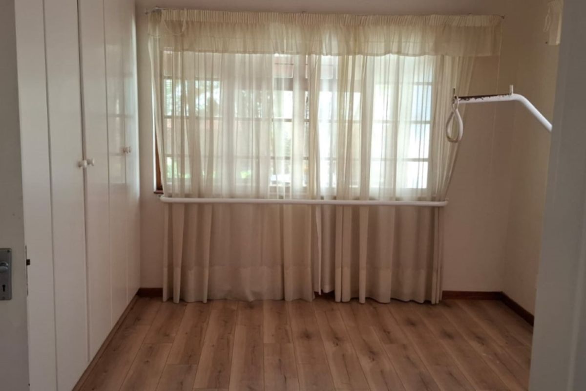 A clean, empty bedroom featuring laminate flooring and built-in cupboards, providing a neutral space ready for personalization.