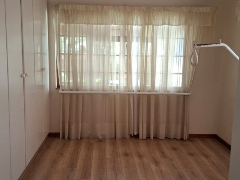 A clean, empty bedroom featuring laminate flooring and built-in cupboards, providing a neutral space ready for personalization.