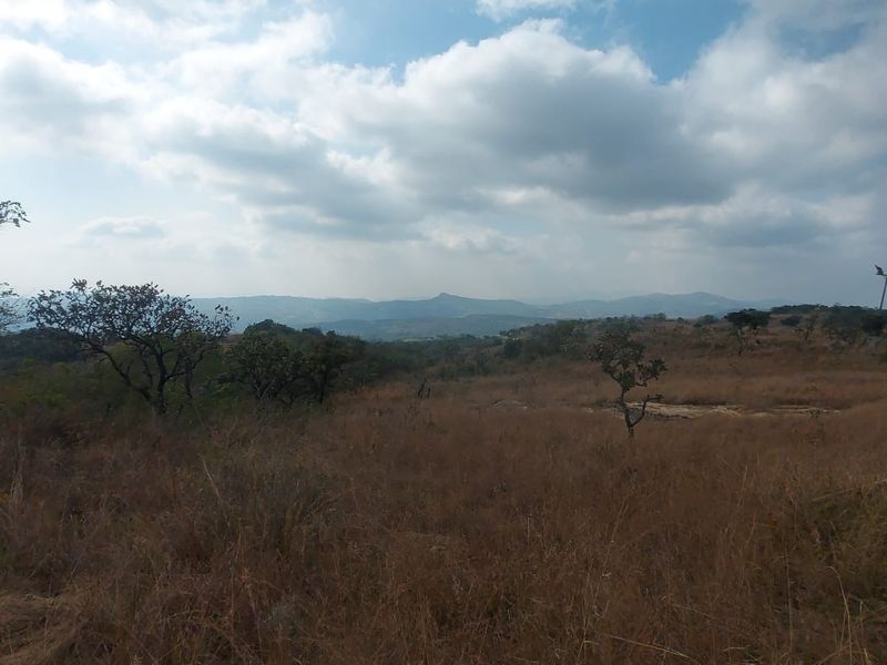 Expansive scenic landscape view featuring rolling hills and natural vegetation under a cloudy sky.