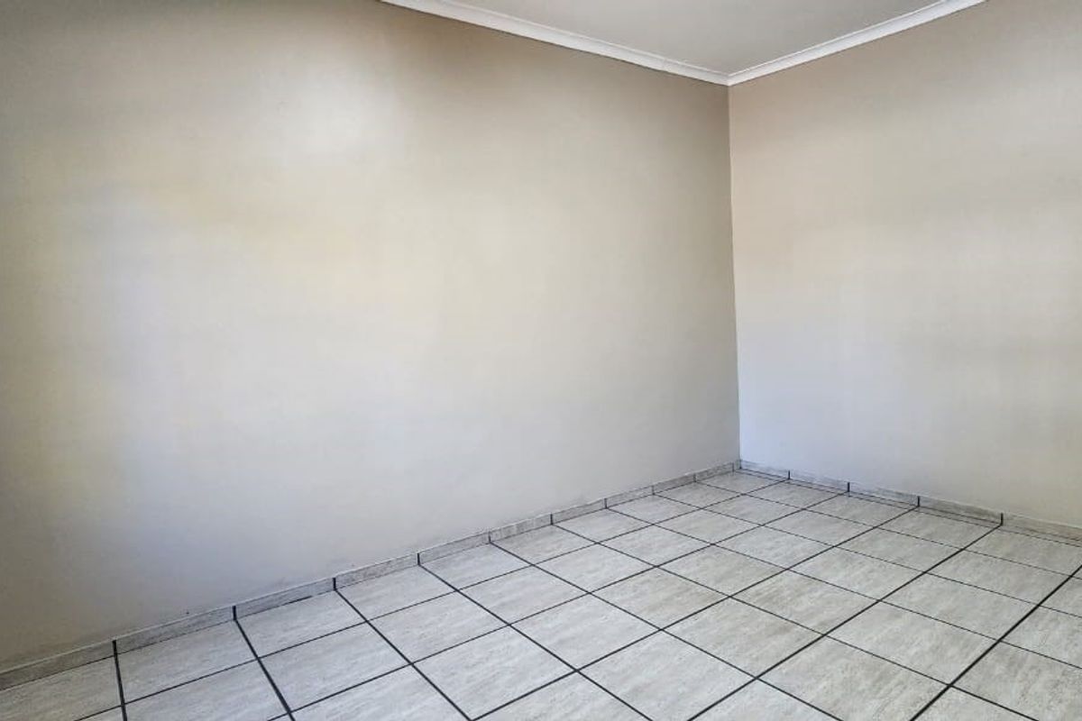 A clean, empty living area featuring neutral wall paint and light-colored ceramic floor tiles, providing a versatile blank canvas for interior design.