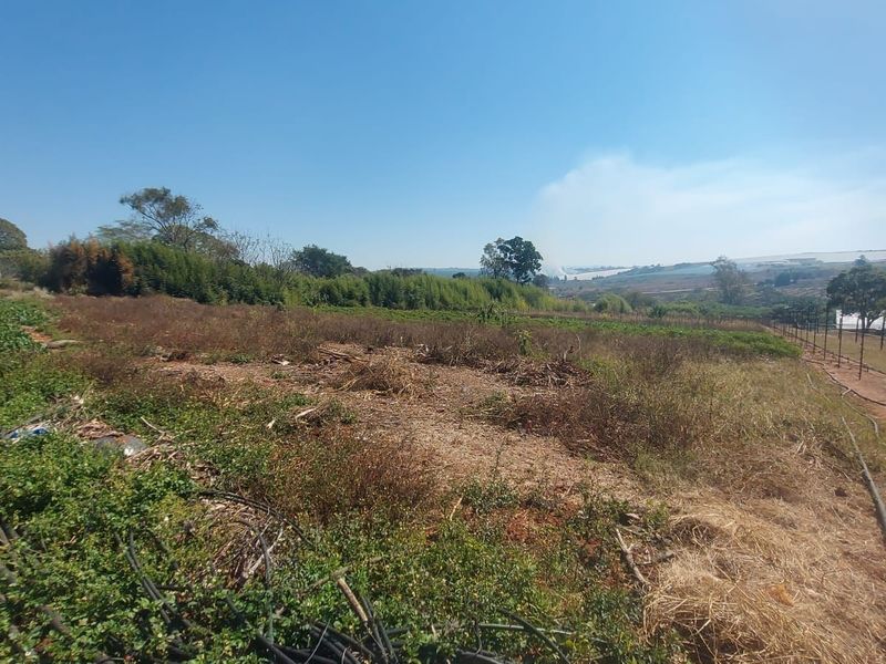 A view of a vacant commercial land plot featuring existing irrigation infrastructure and perimeter electric fencing.