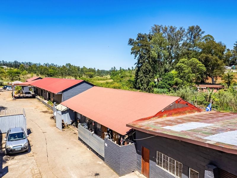 Aerial view of an industrial property featuring multiple warehouse-style buildings with corrugated metal roofs, paved access areas, and perimeter security fencing.