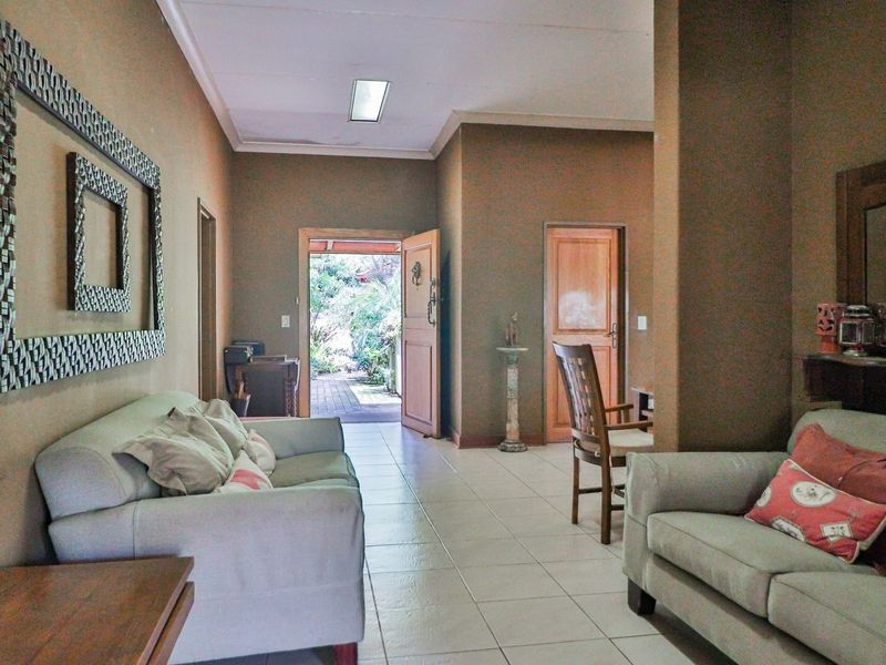 A living room area featuring tiled flooring and direct access to an outdoor garden space through a wooden entrance door.
