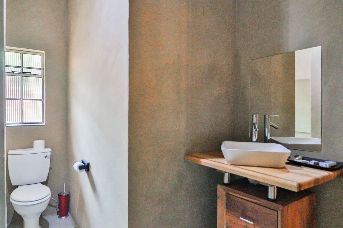 A functional bathroom featuring a modern vessel sink on a wooden vanity, a wall-mounted mirror, and a standard toilet.
