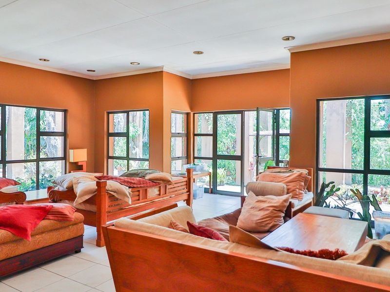 Spacious open-plan living area featuring large aluminium-framed windows and glass doors that provide ample natural light and views of the surrounding garden.