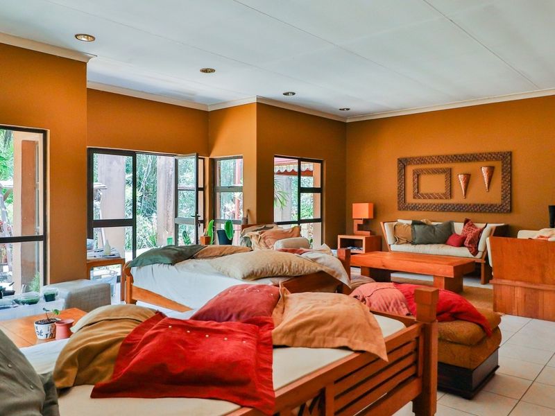 Spacious bedroom featuring tiled flooring, recessed lighting, and large aluminium-framed windows and doors providing natural light and garden access.