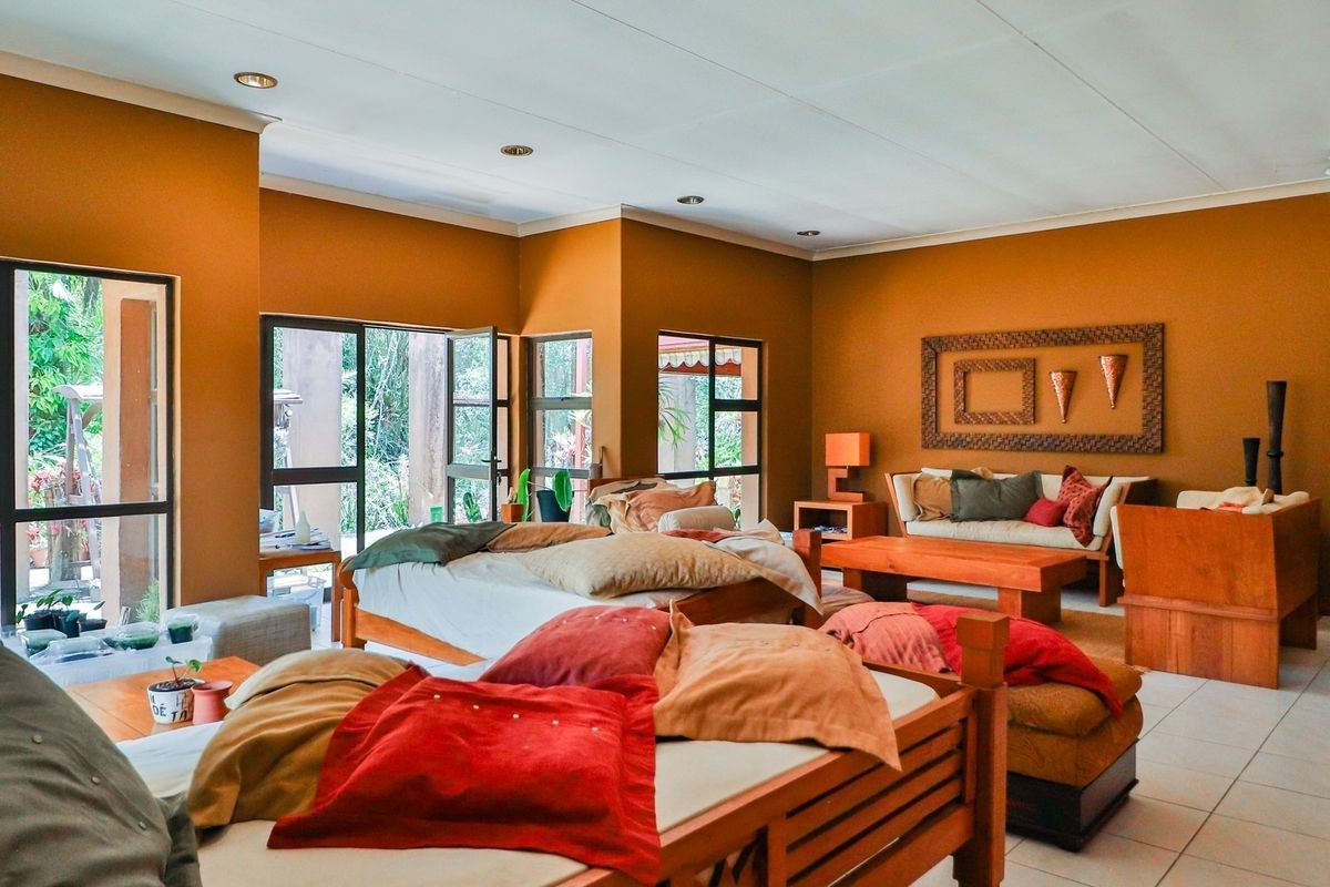 Spacious bedroom featuring tiled flooring, recessed lighting, and large aluminium-framed windows and doors providing natural light and garden access.
